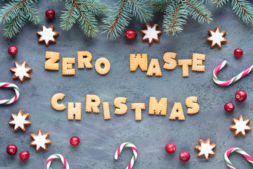Text Zero Waste Christmas made from cookies. Xmas top view. Firr twigs, candy canes, pine cones, star cookies and fresh cranberry, Natural Christmas decorations on grey textured aged sbackground.
