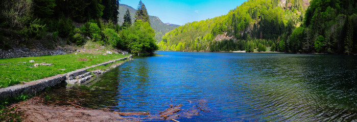 Fototapeta premium An abandoned cabin's stone foundation with its steps touching Petrimanu Lake's water. 