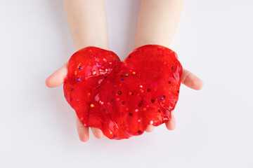 Red slime toy in kids hands on white background. Making slime. Top view. Flatlay