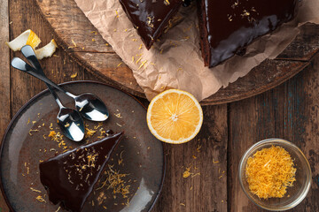 Chocolate cake with a cut piece on a plate and lemon on a wooden background. The view from the top. Concept of culinary backgrounds.