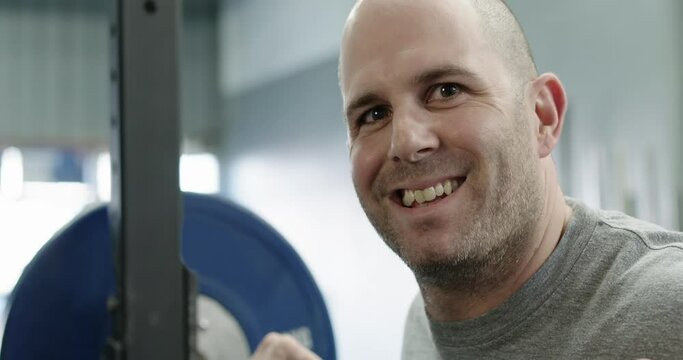 Man smiling in gymnasium at bench press