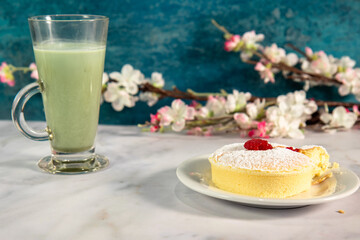 A cup of green matcha tea and a small japanese jiggle sponge cheesecake. 