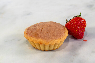 Strawberry Japanese cheese tart on a marble background with a single strawberry 
