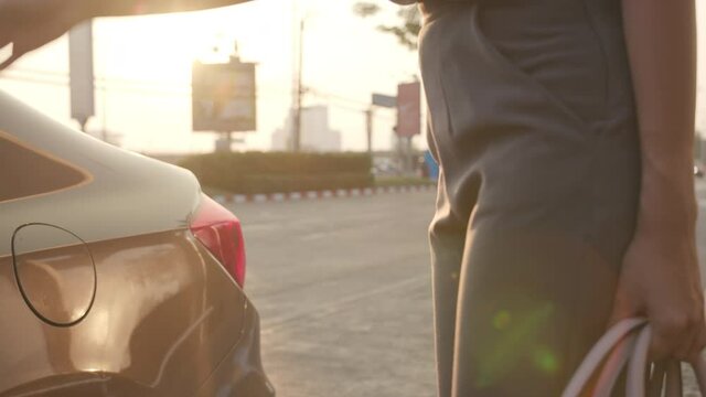 Successful young Asia businesswoman commuter in fashion office clothes entering a taxi or getting into a cab outdoors in urban modern city in the morming. Business on the go to work concept.