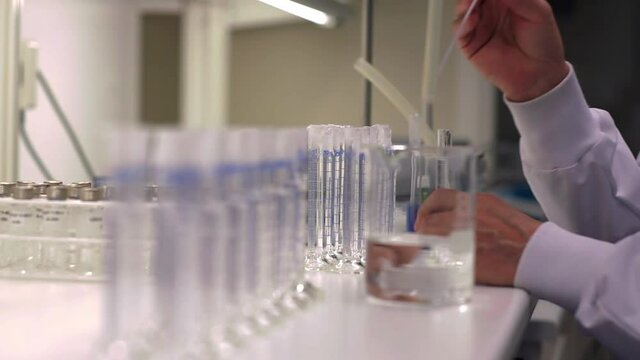 Rack focus shot of scientist dropping samples into test tubes