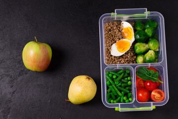 Vegetarian, healthy food in the box.Vegetables and fruits, tomatoes, asparagus, brussels sprouts, apples, pears, grapes on a gray background, top view
