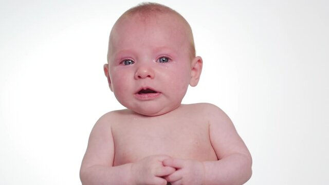 Shirtless curious baby girl looking around and crying