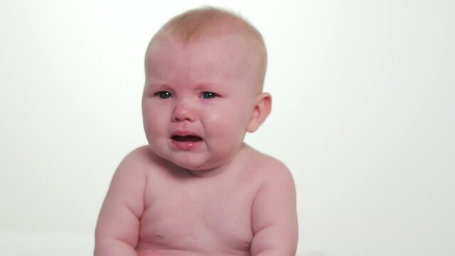 Shirtless curious baby girl looking around then crying