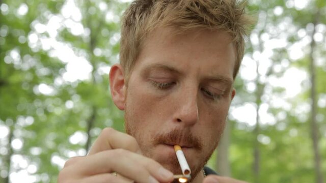 Man smoking cigarette in forest