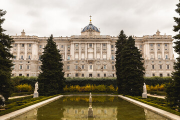 Fototapeta na wymiar royal garden in Spain Madrid capital green bush and shaped trees pond reflection cloudy day Plaza de la Armería