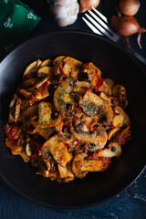 Cooked mushrooms with herbs and spices in black plate. Mushrooms saute.