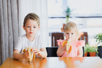 A girl and a boy eating a banana.