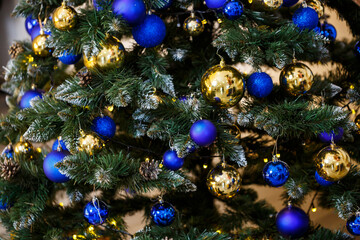 Obraz na płótnie Canvas Decorated Christmas tree close-up. Blue and gold balls and garland lights. Christmas balls on the tree. Winter holiday new year and christmas