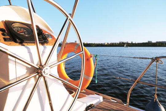 Yacht steering wheel on sunny day wallpaper. Water sport background. White boat cruise banner. Metal rudder on ship. Orange lifebuoy on yacht. Freedom landscape wallpaper. High quality photo