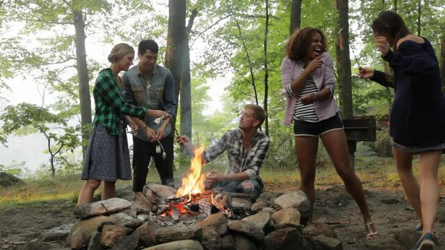 Friends roasting marshmallows at campfire in forest