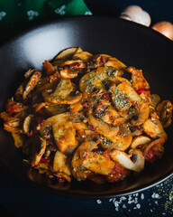 Cooked mushrooms with herbs and spices in black plate. Mushrooms saute.