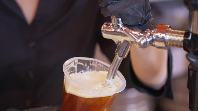 Bartender pouring beer into glass with bubbles close up.