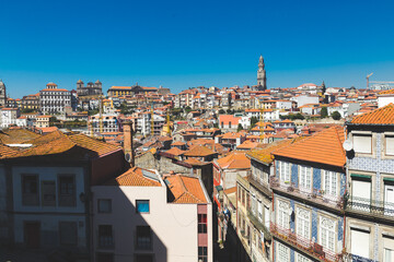Fototapeta na wymiar Porto Portugal old houses building colorful roofs rooftops orange red tower crossblue sky daylight sunny ajulejos streets 