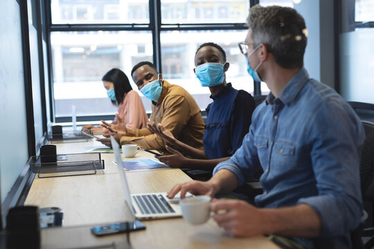 Diverse colleagues wearing face masks working in office
