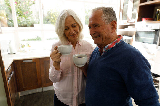 Senior caucasian couple drinking coffee together in the kitchen at home