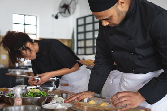 Male middle eastern chef cutting individual ravioli with stuffing at restaurant kitchen