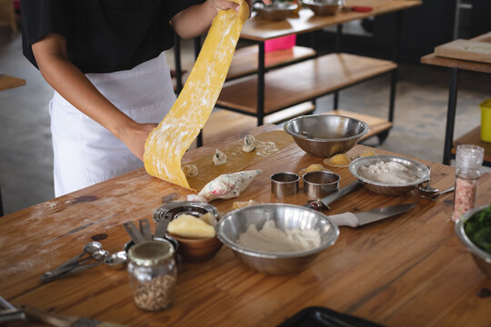 Mid section of chef preparing ravioli with stuffing at restaurant kitchen