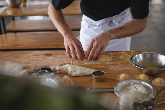 Mid section of chef closing ravioli with stuffing at restaurant kitchen