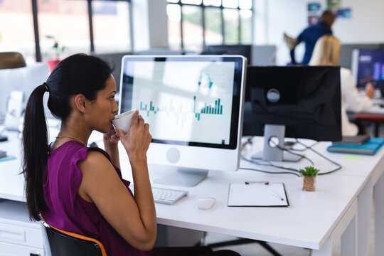 Side view of mixed race woman in office drinking tea