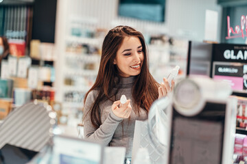 beautiful smiling Asian girl chooses buys cream cosmetics in the store. shopping
