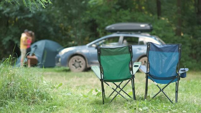 Happy active couple resting at campsite hugging and kissing happily near a car and a tent.