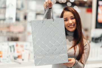 beautiful girl holds a gray holiday package in the store. selective focus