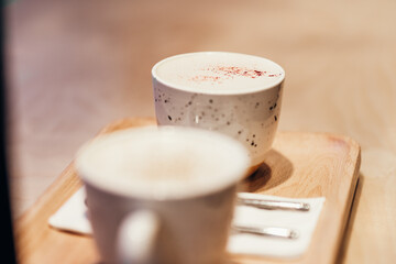 Two mugs with morning coffee on a wooden board on the table, horizontal photo