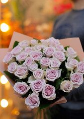Fresh beautiful flower. Man holding a big delicate flower bouquet of roses wrapped in paper.