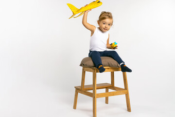 Toddler girl sitting on and posing with a yellow plane toy. Gender stereotypes.
