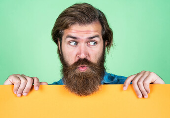 look here. unshaven guy with groomed long hair. barbershop and hairdresser. male beauty and fashion. surprised bearded man. brutal caucasian hipster hold paper shit, copy space. human emotions