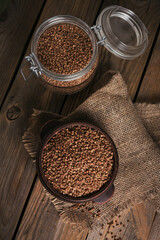 Bowl of dry raw buckwheat groats on a wooden background. Cooking buckwheat porridge concept.
