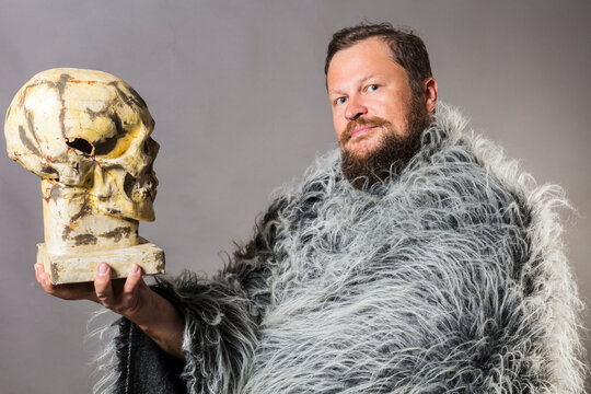 Solid bearded man in a fur mantle with skull studio portrait