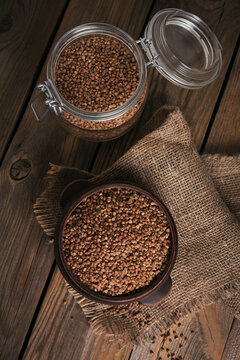 Bowl of dry raw buckwheat groats on a wooden background. Cooking buckwheat porridge concept. © svittlana