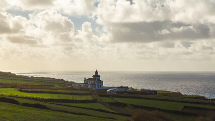 Fototapeta na wymiar Sao Miguel island Portugal shore lighthouse Atlantic ocean day sunshine sunlight white clouds water field green 