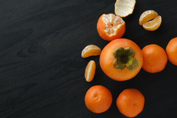Fruits, persimmon and tangerines on black background..