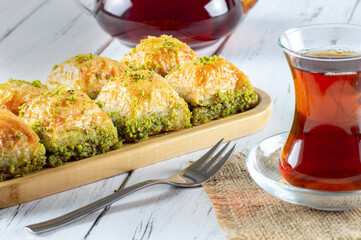 Traditional turkish dessert pistachio antep baklava with turkish black tea on rustic table, ...