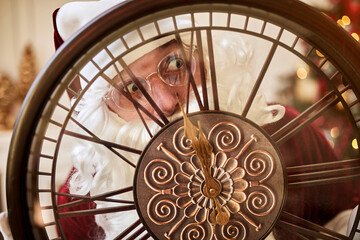 Five minutes to New year or Christmas midnight.  Happy Santa Claus shows on the clock