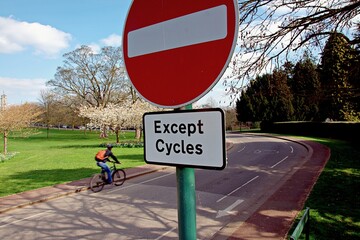 Road sign No Entry except for cycles, with blue cloudy sky.