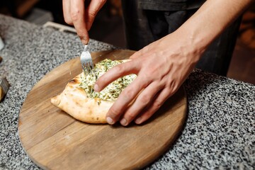 the hands of the cook prepare khachapuri on the kitchen table. cook a traditional Georgian treat of...