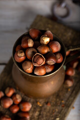 Shelled hazelnuts in an old copper jug. Hazelnuts on wooden background.
