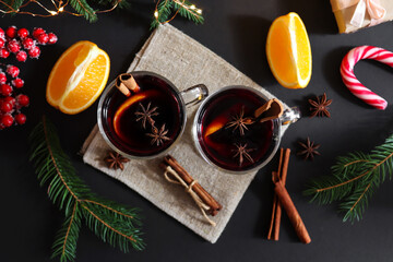Obraz na płótnie Canvas Two glasses of mulled wine with cinnamon and oranges on a festive Christmas background. Hot Christmas drinks. Flat lay, top view