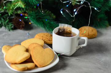 Homemade cookies in the shape of a heart in a white plate with a mug and a tea bag