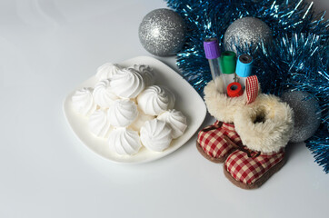 Fototapeta na wymiar A few meringues on a plate with Christmas decorations and medical test tubes on a white table.