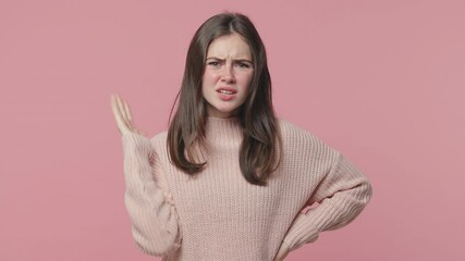 Shocked irritated brunette young woman 20s in pastel sweater isolated on pink background studio. People lifestyle concept. Looking camera swearing spreading hands ask what standing with arms akimbo