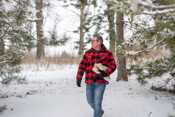 Man in red plaid jacket carrying firewood